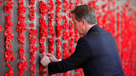 British Prime Minister David Cameron places a poppy along the Roll of Honour during a visit to the Australian War Memorial in Canberra.