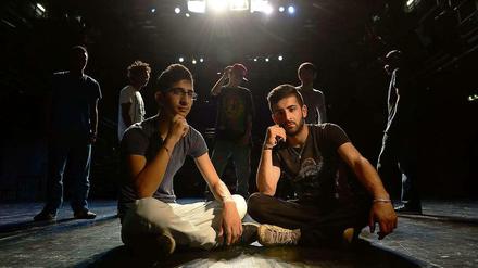 Zwei junge Männer aus Syrien sitzen auf einer Theaterbühne.