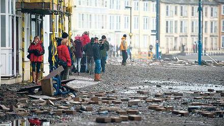 Mit Ziegeln und Unrat sind die Uferstraßen der walisischen Küstenstadt Aberystwyth übersäht, nachdem Sturmfluten über den Ort hereingebrochen waren.