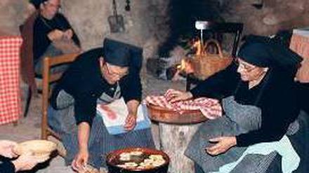 In Ruinen kochen Frauen über offenem Feuer für das Weihnachtsfest. 