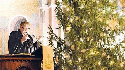 Ein Pfarrer pregigt. Neben ihm steht ein Christbaum.