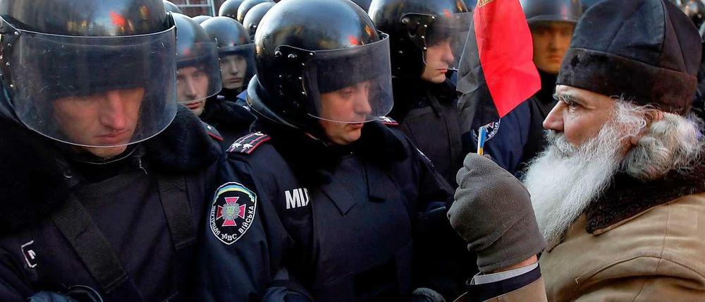 Mehrere tausend Demonstranten haben am Dienstagmorgen in der ukrainischen Hauptstadt Kiew bei einer Kundgebung vor dem Parlament die Abwahl der Regierung gefordert. Einer der Protestanten hielt der Polizei dabei eine Flagge entgegen.