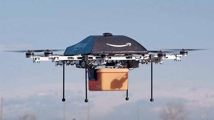 Zustellung ohne Bote. Für Amazon liegt die Zukunft der Logistik in der Luft. Der „Octocopter“, so genannt wegen der acht Motoren, trägt das Logo des Konzerns. Der geschwungene Pfeil soll ein Lächeln symbolisieren. Unten hängt eine gelbe Box für die bestellte Ware. Foto: dpa