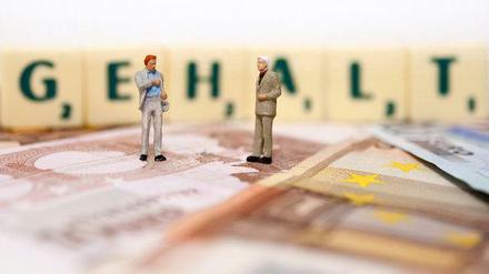 Brutto-Netto-Rechner: Zwei Männer stehen auf Geldscheinen, hinter ihnen steht das Wort Gehalt auf Scrabble-Buchstaben