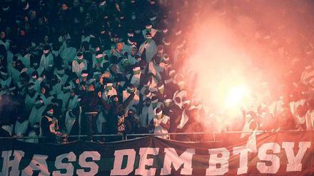 Geisterspiel. Weiß vermummt zündeln Chaoten im Block von Hannover 96 und schmähen Eintracht Braunschweig mit Plakaten.  Foto: dpa