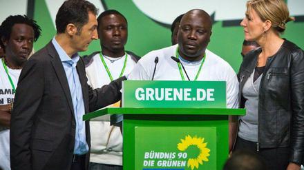 Cem Özdemir (li.) und die neue Bundesvorsitzende Simone Peter (re.) hören der Rede des Nigerischen Flüchtlings Bashir Zakari zu.