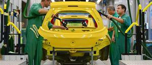 Bei Opel in Eisenach arbeiten Männer in grünen Overalls an einem Kleinwagen, der gelb lackeirt ist. 