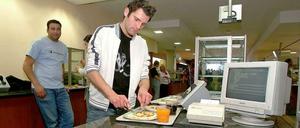 Ein Student steht mit seinem Essenstablett an der Mensa-Kasse.