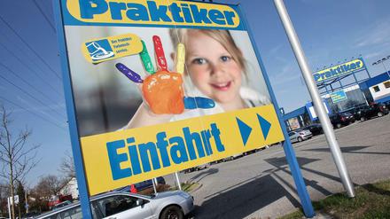 An einer Einfahrt eines Praktiker-Marktes steht ein Praktiker-Plakat mit einem Kind.