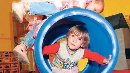Zwei Kita-Kinder spielen mit einer Tonne.