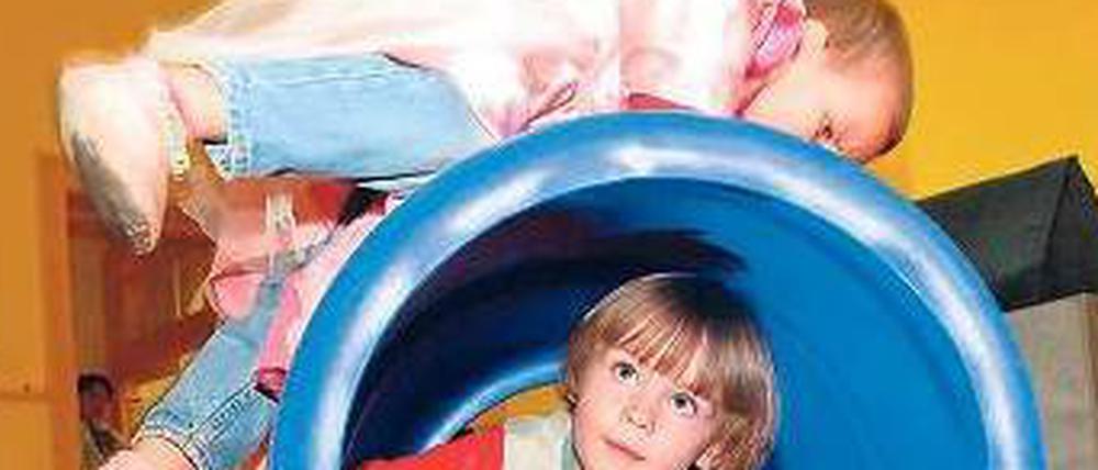 Zwei Kita-Kinder spielen mit einer Tonne.