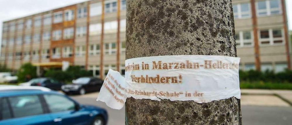 Ein zerrissenes Plakat mit der Aufschrift "Asylbewerberheim in Marzahn-Hellersdorf verhindern!" hängt an einem Laternenpfahl vor der geplanten Notunterkunft für Flüchtlinge im ehemaligen Max-Reinhardt-Gymnasium in Hellersdorf.