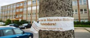 Ein zerrissenes Plakat mit der Aufschrift "Asylbewerberheim in Marzahn-Hellersdorf verhindern!" hängt an einem Laternenpfahl vor der geplanten Notunterkunft für Flüchtlinge im ehemaligen Max-Reinhardt-Gymnasium in Hellersdorf.