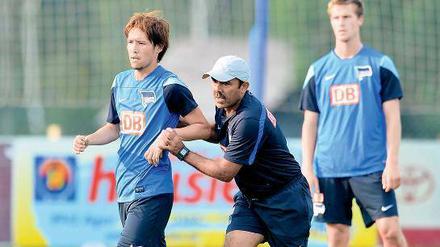 Hertha-Trainer Jos Luhukay schiebt Spieler Hajime Hosogai über den Trainingsplatz.