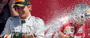 Augen zu und durch: Fernando Alonso (r.) ertrug die Sektdusche von Gewinner Nico Rosberg.