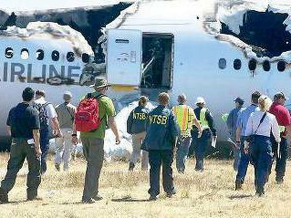 Mitarbeiter der Sicherheitsbehörde NTSB untersuchen das Wrack der Boeing 777.