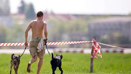 Körperkult. Ein Mann zeigt auf dem Tempelhofer Feld, was er außer zwei Hunden noch so zu bieten hat.