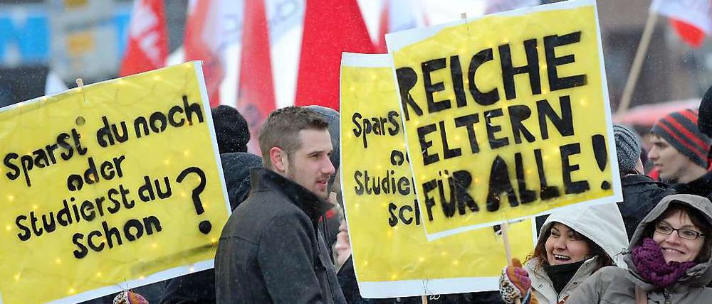 Junge Studenten, die auf Plakaten fordern: "Suche reiche Eltern."