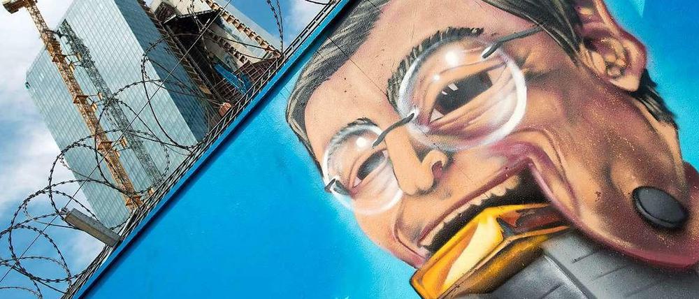 Nimmersatt: Ein Graffitti am Bauzaun des Neubaus der Europäischen Zentralbank (EZB) in Frankfurt zeigt EZB-Chef Mario Draghi mit einem Goldbarren im Mund.