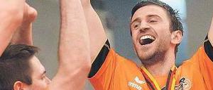 20 Kilogramm schwer und unheimlich begehrt. Roko Sikiric lässt sich von seinen Kollegen für das Stemmen der Meistertrophäe bejubeln. Foto: dpa