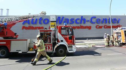 Fahrzeuge der Feuerwehr stehen vor der Autowaschanlage in Mitte, in der zuvor ein Brand ausgebrochen war. 