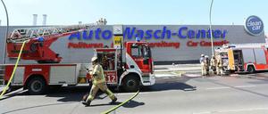 Fahrzeuge der Feuerwehr stehen vor der Autowaschanlage in Mitte, in der zuvor ein Brand ausgebrochen war.