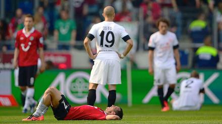Niedergeschlagen: Die Hannoveraner Spieler und die Mainzer stehen nach dem Spiel auf dem Rasen.