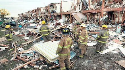Fassungslos stehen Feuerwehrleute vor einer vollständig zerstörten Hausreihe in der Nähe des Explosionsortes. 