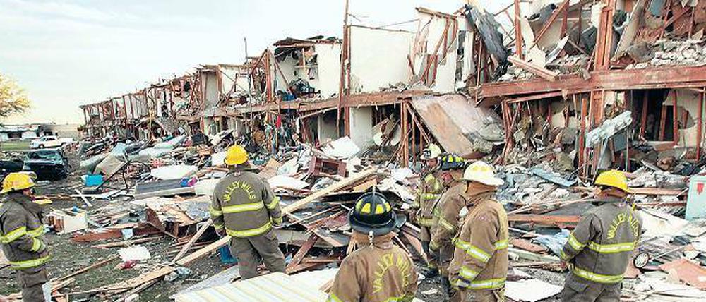 Fassungslos stehen Feuerwehrleute vor einer vollständig zerstörten Hausreihe in der Nähe des Explosionsortes.