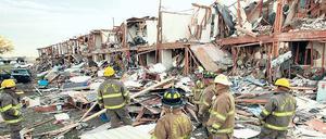Fassungslos stehen Feuerwehrleute vor einer vollständig zerstörten Hausreihe in der Nähe des Explosionsortes. 