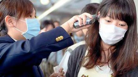 Ein Mitarbeiterin misst die Temperatur einer Reisenden auf dem Sungshan Airport in Taipei. 