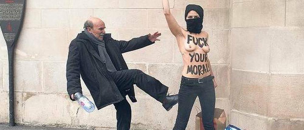 Ein Mann vor einer Moschee in Paris tritt nach einer Aktivistin, die gegen Frauen-Unterdrückung im Islam protestiert.