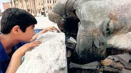 Ein Junge mit einer zerstörten Statue von Hafez al Assad, Vater von Baschar. Foto: Reuters