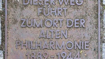 Die auf dem Boden eingelassene Gedenktafel für Berlins Alte Philharmonie, deren entscheidende Umbauplanung zum legendären Philharmoniker-Auftrittsort vor 125 Jahren begann, befindet sich im Hof des Hauses Bernburger Straße 21 (Kreuzberg).