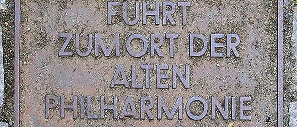 Die auf dem Boden eingelassene Gedenktafel für Berlins Alte Philharmonie, deren entscheidende Umbauplanung zum legendären Philharmoniker-Auftrittsort vor 125 Jahren begann, befindet sich im Hof des Hauses Bernburger Straße 21 (Kreuzberg).