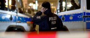 Geiselnahme in einer Bank in Berlin-Zehlendorf. Ein Polizist telefoniert vor zwei Einsatzwagen.