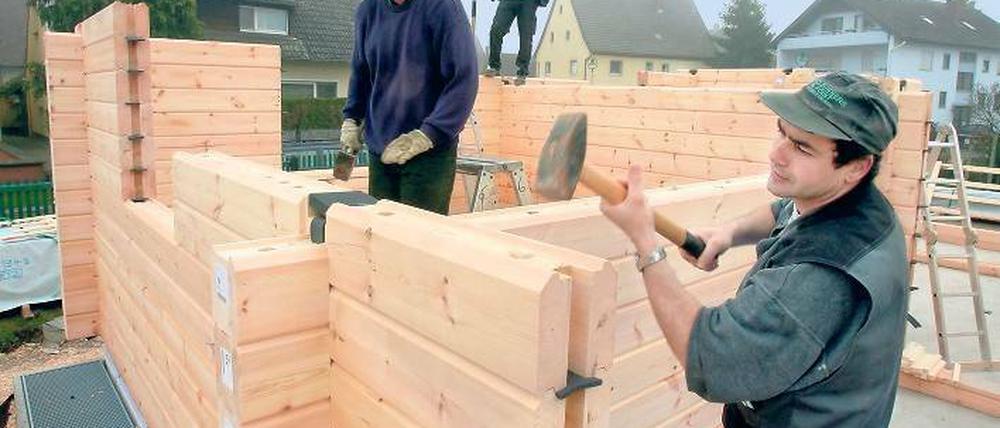 Latte für Latte statt Stein auf Stein: Bauarbeiter ziehen mit Balken aus arktischem Fichtenholz ein Holzhaus hoch.