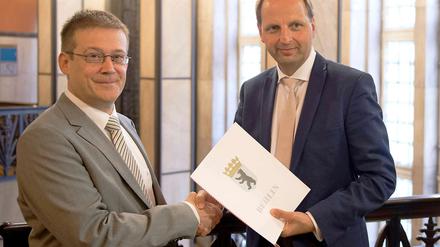 Der neue Opferschutzbeauftragte Roland Weber (l.) bekommt von Justizsenator Thomas Heilmann die Ernennungsurkunde überreicht.
