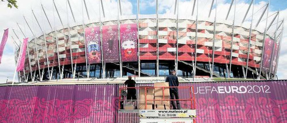 Noch zu tun. Arbeiter befestigen einen Sichtschutz am Nationalstadion in Warschau, in dem am Freitag das EM-Eröffnungsspiel Polen gegen Griechenland ausgetragen wird.