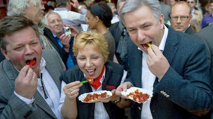 Das Berliner Original: Klaus Wowereit beim Verspeisen einer Currywurst von Curry 36. Bild mit Curry-36-Chefin, Vera Stenschke und Inhaber Lutz Michael Stenschke.
