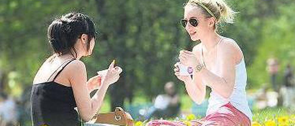 Hochsommerliche Temperaturen. Zwei Frauen im Englischen Garten in München.