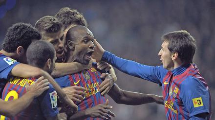 Eric Abidal (m.) wird von Weltfußballer Lionel Messi (r.) und seinen Mannschaftskameraden umjubelt.