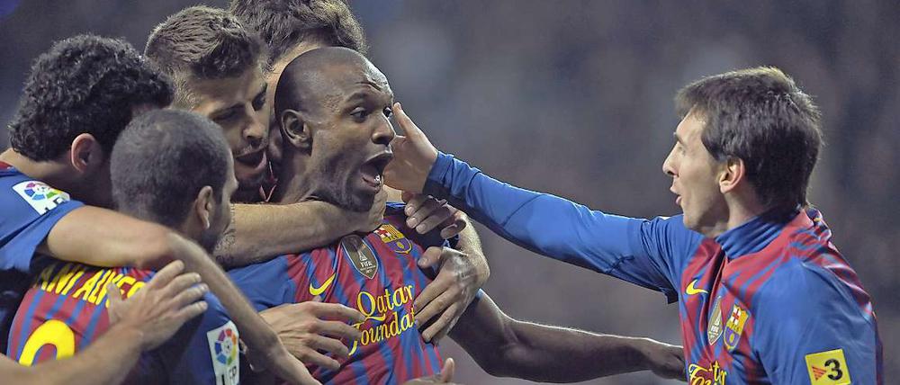 Eric Abidal (m.) wird von Weltfußballer Lionel Messi (r.) und seinen Mannschaftskameraden umjubelt.