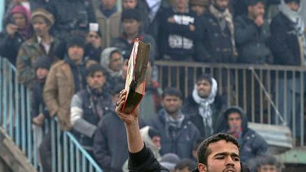 Ein afghanischer Demonstrant hält ein halbverbranntes Koranexemplar in die Höhe.