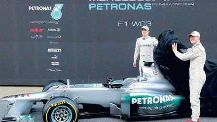 Schaut her, da ist es. Michael Schumacher und Nico Rosberg lüften das Geheimnis von Mercedes und haben offensichtlich viel Freude daran. Das neue Auto fahre sich auf jeden Fall zuverlässiger als das alte, sagen die beiden Formel-1-Piloten. Foto: AFP