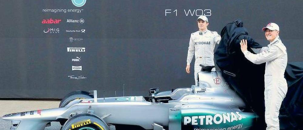 Schaut her, da ist es. Michael Schumacher und Nico Rosberg lüften das Geheimnis von Mercedes und haben offensichtlich viel Freude daran. Das neue Auto fahre sich auf jeden Fall zuverlässiger als das alte, sagen die beiden Formel-1-Piloten. Foto: AFP