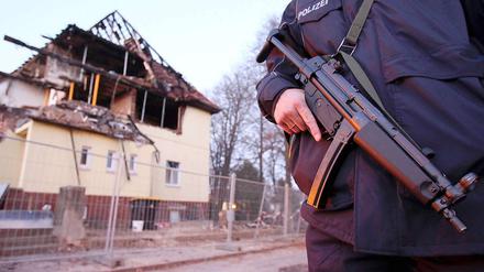 Ein Polizist mit Maschinenpistole steht in Zwickau vor dem durch eine Explosion zerstörten Haus, das von den NSU-Mitgliedern Uwe Mundlos, UweBöhnhardt und Beate Zschäpe bewohnt wurde 