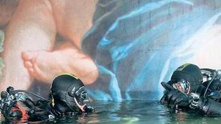 Marinetaucher schwimmen im Inneren des Wracks an einem Deckengemälde entlang. 