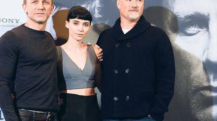 Pulli, Top, Jacke. Daniel Craig, sonst als James Bond aktiv, und Regisseur David Fincher (r.) werben hochgeschlossen für die Stieg-Larsson-Verfilmung „Verblendung“. Hauptdarstellerin Rooney Mara hat dagegen Hitze. Kinostart ist am 12. Januar. Foto: Clemens Bilan/dapd