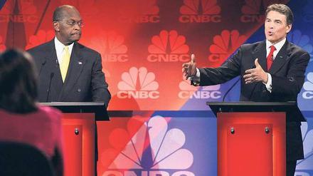 Wahlkampfzirkus. Rick Perry, Gouverneur von Texas, hatte vor einem Millionenpublikum einen schweren Aussetzer und redete sich um Kopf und Kragen. Seither bewegt sein Blackout die ganze Nation. Sein Kontrahent Herman Cain (links) kämpft derweil mit den Vorwürfen mehrerer Frauen, die sich von ihm sexuell belästigt fühlten. Foto: Scott Olson/Getty Images/AFP